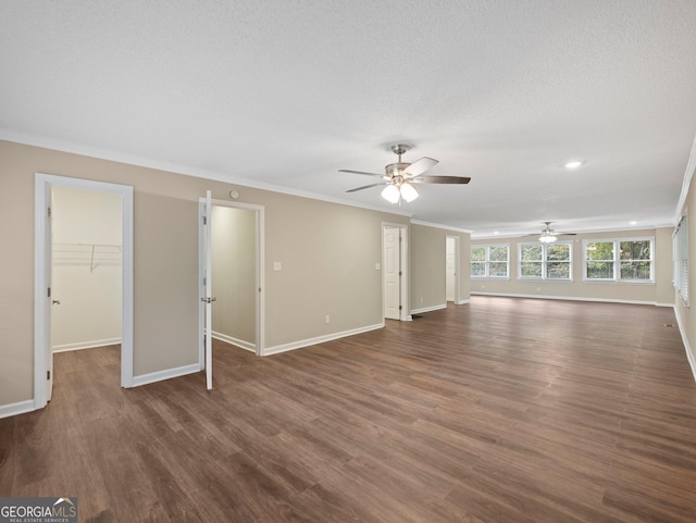 unfurnished living room featuring ceiling fan, a textured ceiling, dark hardwood / wood-style flooring, and ornamental molding