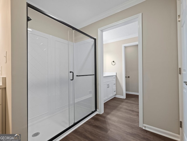 bathroom with hardwood / wood-style flooring, walk in shower, ornamental molding, and vanity