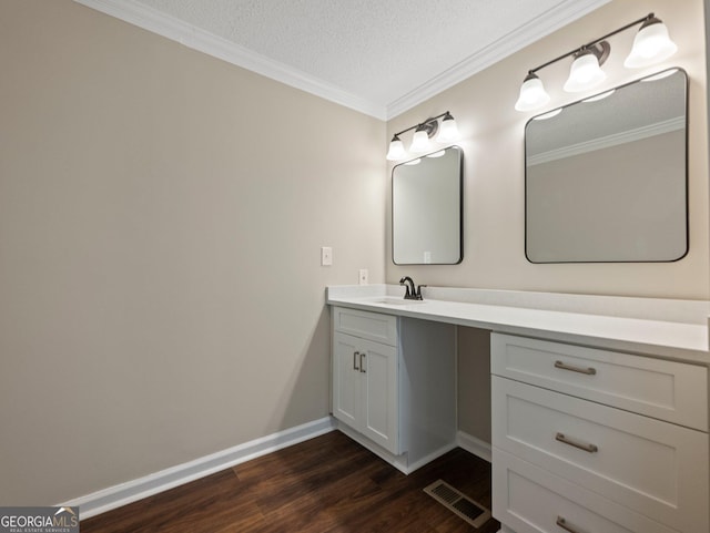 bathroom with a textured ceiling, ornamental molding, hardwood / wood-style floors, and vanity