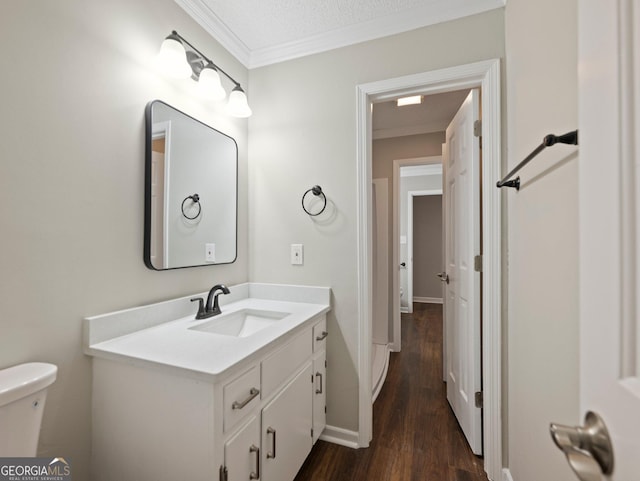 bathroom with toilet, vanity, wood-type flooring, crown molding, and a textured ceiling