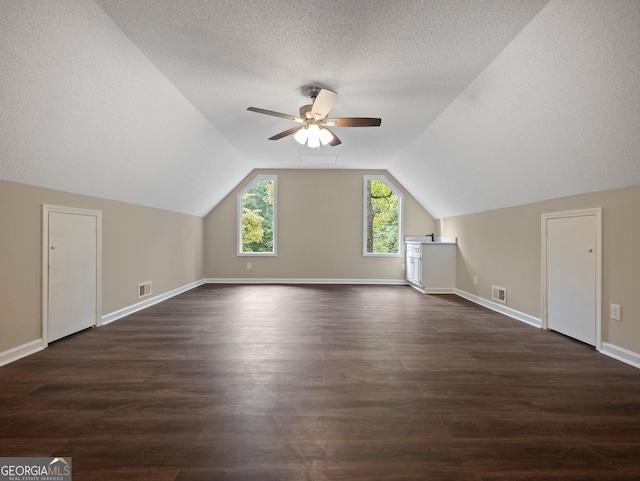 additional living space with vaulted ceiling, ceiling fan, a textured ceiling, and dark hardwood / wood-style floors