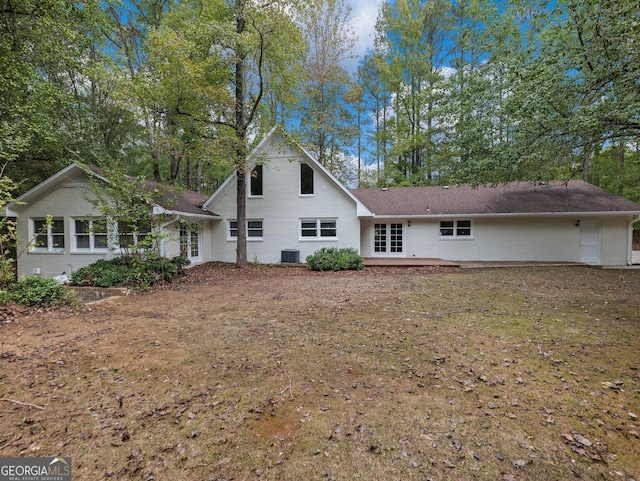 back of house with central air condition unit and a lawn