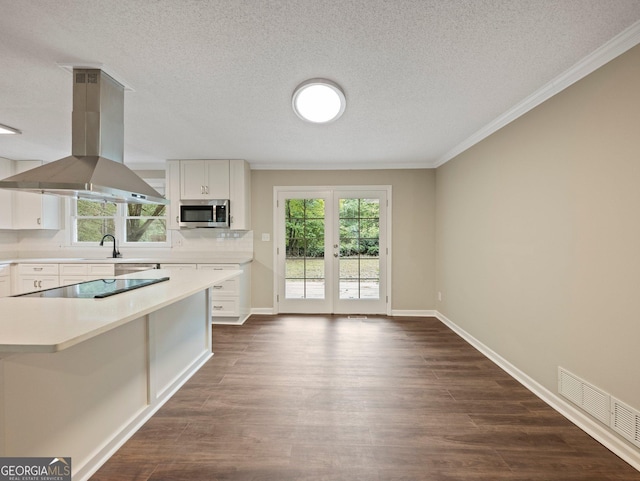 kitchen with a wealth of natural light, white cabinetry, black electric cooktop, and island range hood