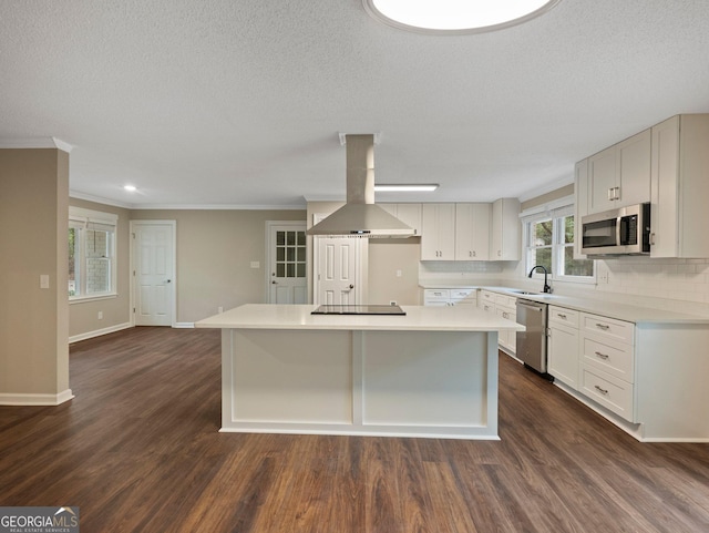 kitchen with a center island, island exhaust hood, stainless steel appliances, tasteful backsplash, and ornamental molding