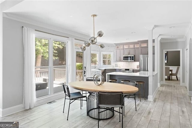 dining space featuring light hardwood / wood-style flooring, crown molding, and sink