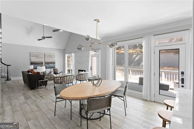 dining room featuring lofted ceiling, ceiling fan with notable chandelier, and light wood-type flooring