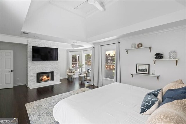 bedroom with a fireplace, dark hardwood / wood-style floors, a raised ceiling, and ceiling fan