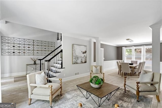 living room featuring ornate columns, crown molding, and light hardwood / wood-style floors