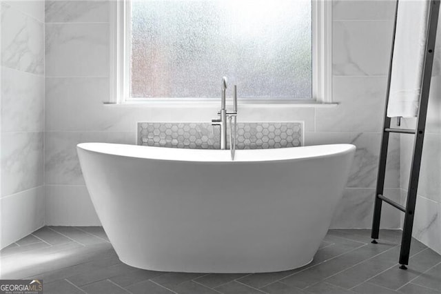 bathroom with a bathtub, tile patterned floors, and tile walls