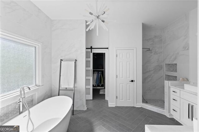 bathroom featuring an inviting chandelier, tile walls, vanity, and plus walk in shower