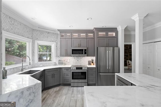 kitchen featuring light stone countertops, ornamental molding, appliances with stainless steel finishes, and sink