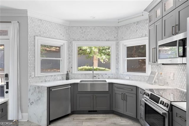 kitchen featuring sink, gray cabinetry, backsplash, stainless steel appliances, and crown molding