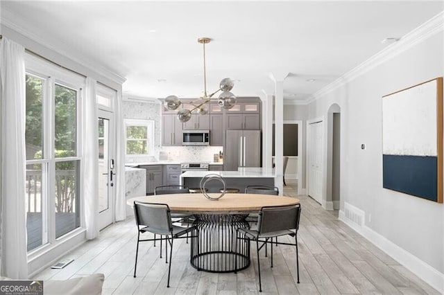 dining space featuring a notable chandelier, light hardwood / wood-style floors, and ornamental molding