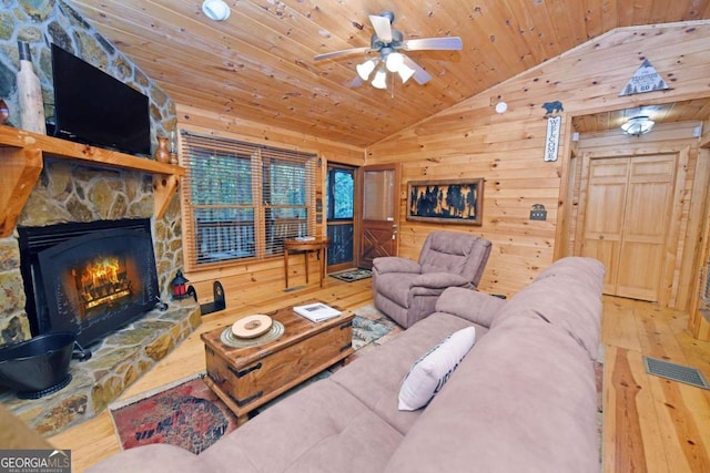 living room featuring a stone fireplace, hardwood / wood-style flooring, wooden ceiling, vaulted ceiling, and wood walls