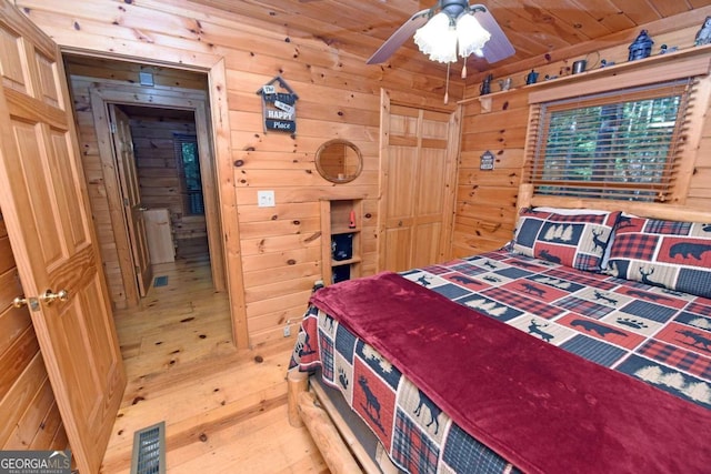 bedroom with light wood-type flooring, wooden walls, ceiling fan, and wood ceiling