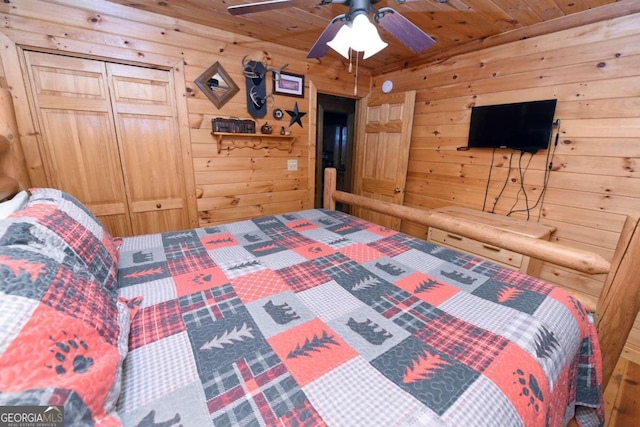 bedroom with ceiling fan, wood walls, a closet, and wood ceiling