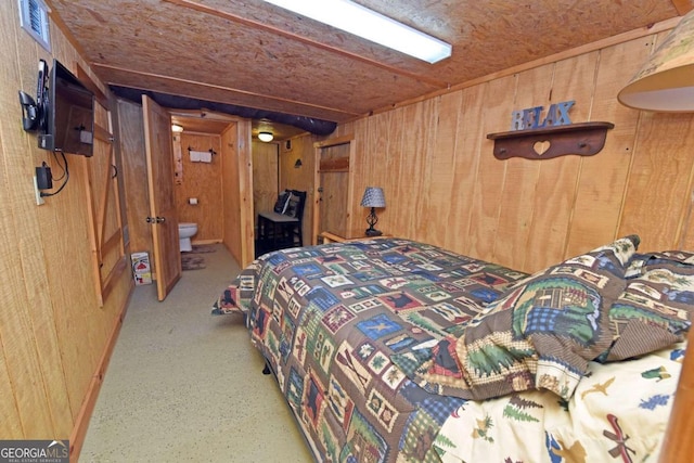 bedroom featuring ensuite bathroom and wood walls