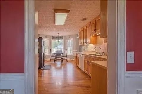 kitchen featuring light hardwood / wood-style floors, sink, hanging light fixtures, and stainless steel appliances