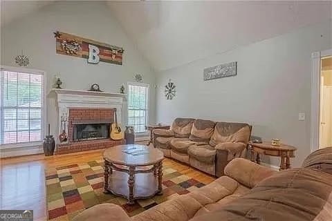 living room featuring hardwood / wood-style floors, high vaulted ceiling, and a fireplace