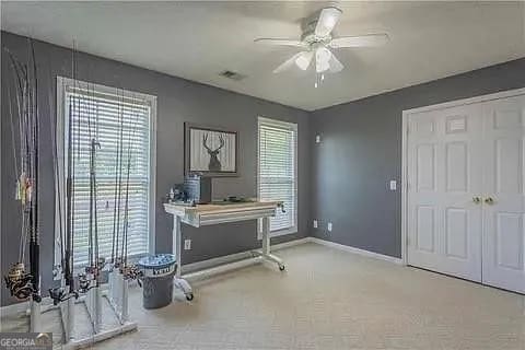 carpeted office featuring ceiling fan