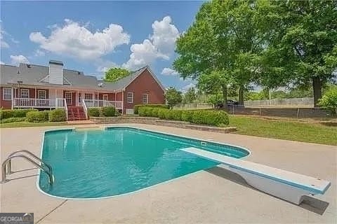 view of swimming pool with a diving board and a patio area