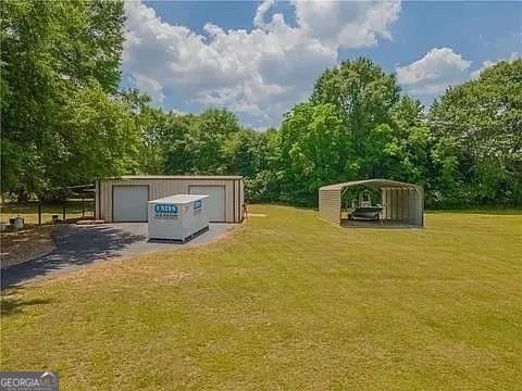 view of yard with a carport and an outbuilding