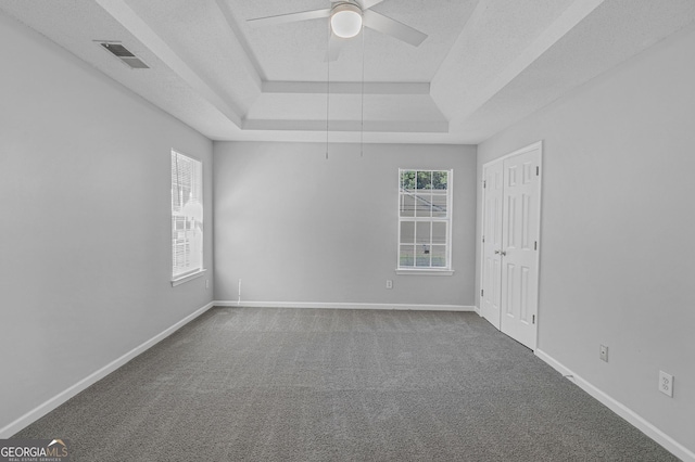 carpeted spare room with a raised ceiling, a textured ceiling, and ceiling fan