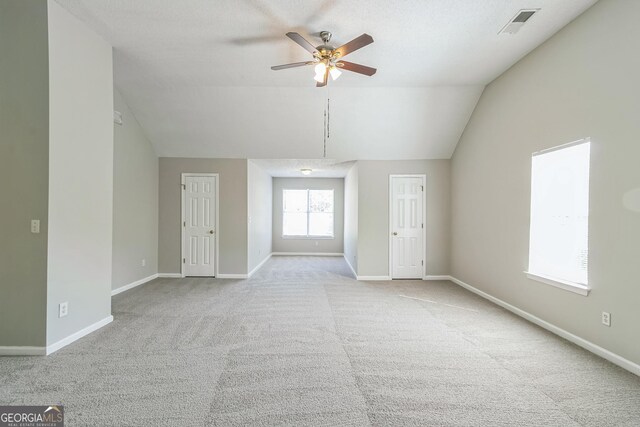 unfurnished living room featuring lofted ceiling, visible vents, a ceiling fan, carpet floors, and baseboards