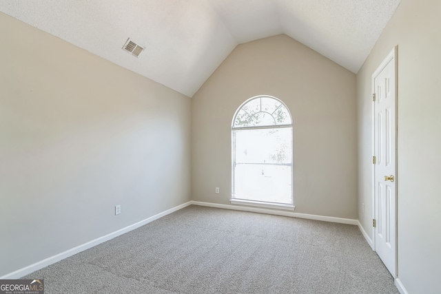 carpeted spare room with a textured ceiling and lofted ceiling