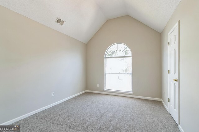 carpeted empty room with vaulted ceiling, visible vents, and baseboards