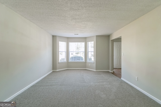 carpeted empty room with a textured ceiling