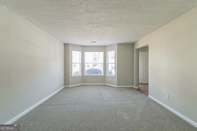 carpeted spare room with baseboards and a textured ceiling