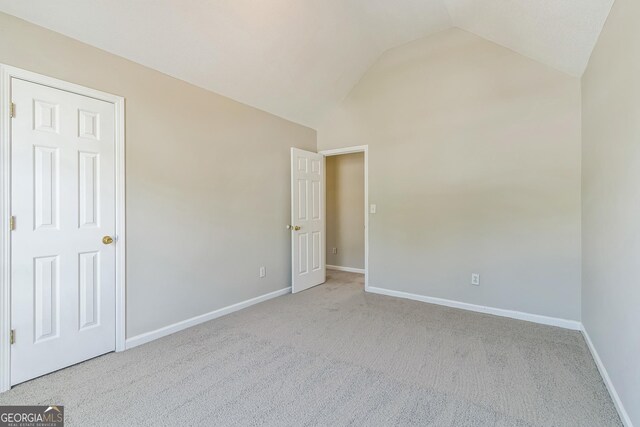 unfurnished bedroom with baseboards, lofted ceiling, and carpet
