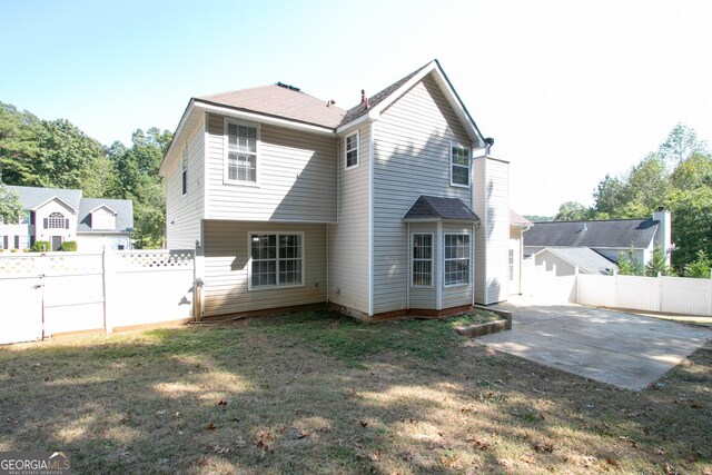 back of property with fence, a lawn, and a patio