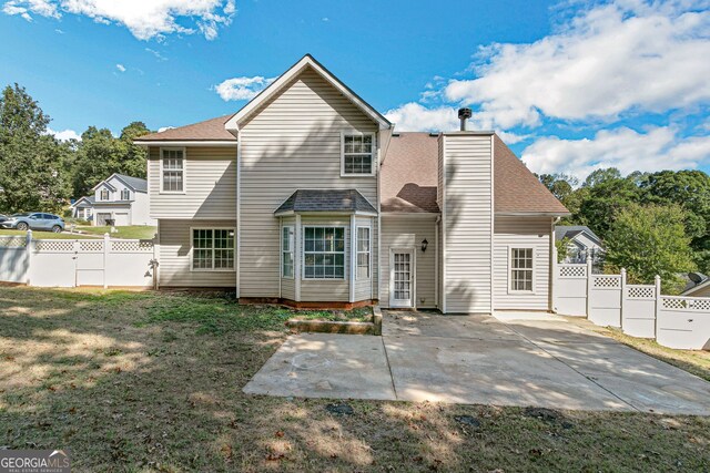 back of property with a lawn, roof with shingles, a patio area, and a fenced backyard