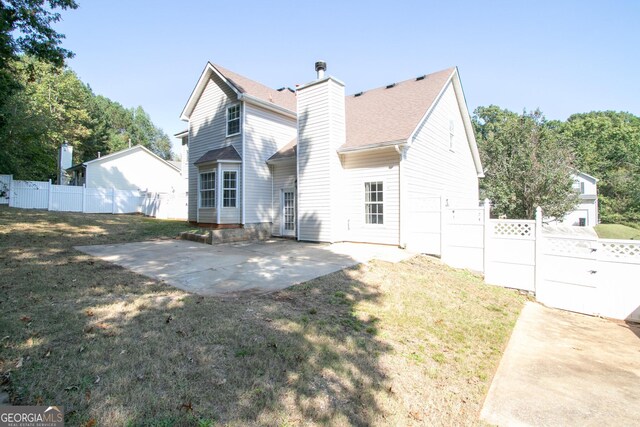 back of property with a chimney, a yard, fence, and a patio area