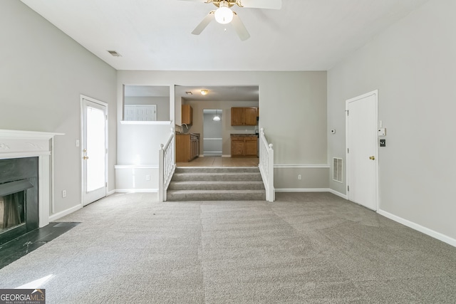 unfurnished living room featuring ceiling fan and carpet floors