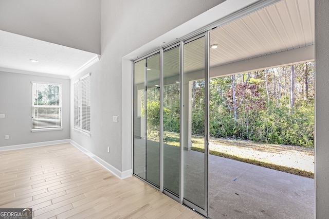 doorway featuring ornamental molding and light wood-type flooring