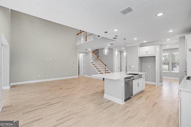 kitchen with a center island with sink, sink, dishwasher, white cabinets, and pendant lighting