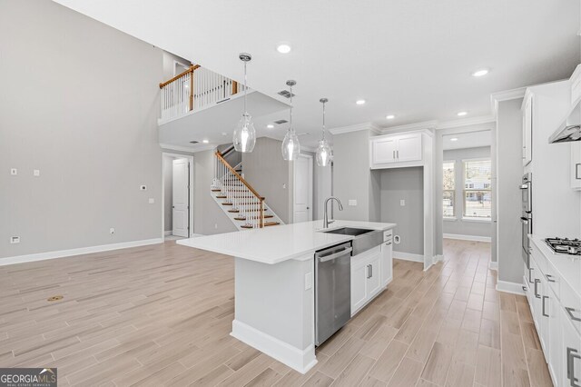 kitchen with ventilation hood, light hardwood / wood-style floors, white cabinets, and a kitchen island with sink