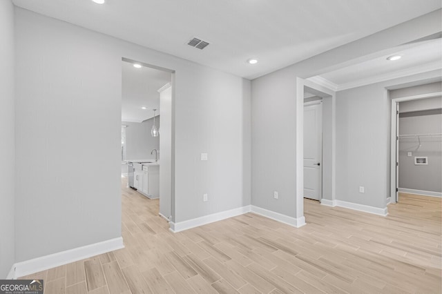 unfurnished bedroom with light wood-type flooring, sink, and a walk in closet