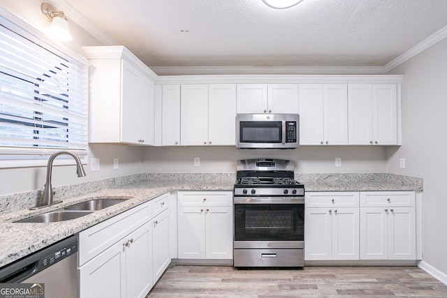 kitchen with stainless steel appliances, crown molding, sink, and white cabinetry