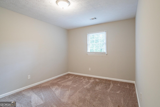 carpeted spare room with visible vents, baseboards, and a textured ceiling