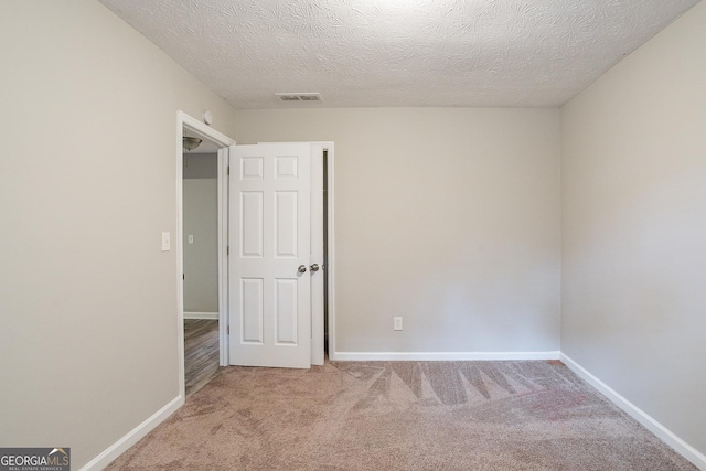 unfurnished bedroom with visible vents, baseboards, a textured ceiling, and carpet floors