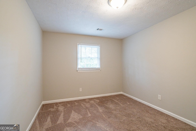 carpeted empty room featuring visible vents, baseboards, and a textured ceiling