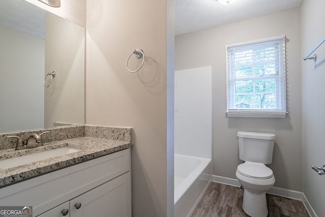 bathroom featuring vanity, a textured ceiling, hardwood / wood-style floors, and toilet