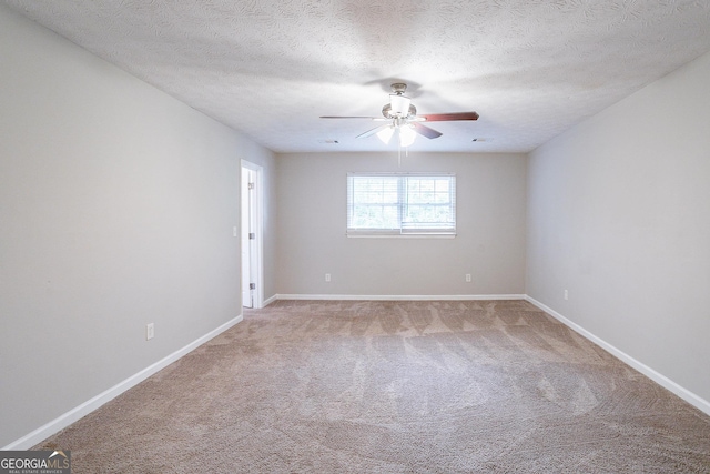 empty room featuring ceiling fan, a textured ceiling, light carpet, and baseboards