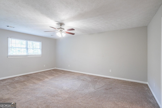 carpeted empty room featuring a textured ceiling, baseboards, a ceiling fan, and visible vents