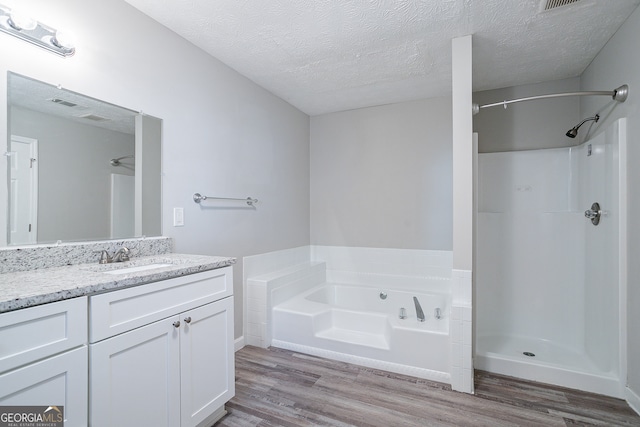 bathroom featuring a textured ceiling, hardwood / wood-style flooring, vanity, and shower with separate bathtub