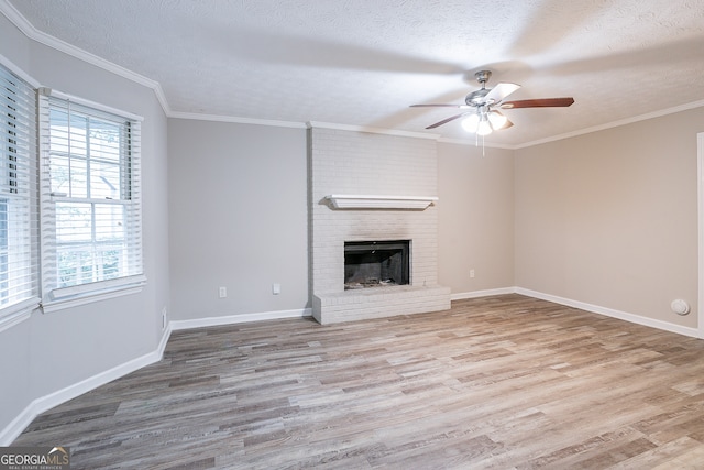 unfurnished living room featuring ceiling fan, light wood-type flooring, a brick fireplace, and a textured ceiling